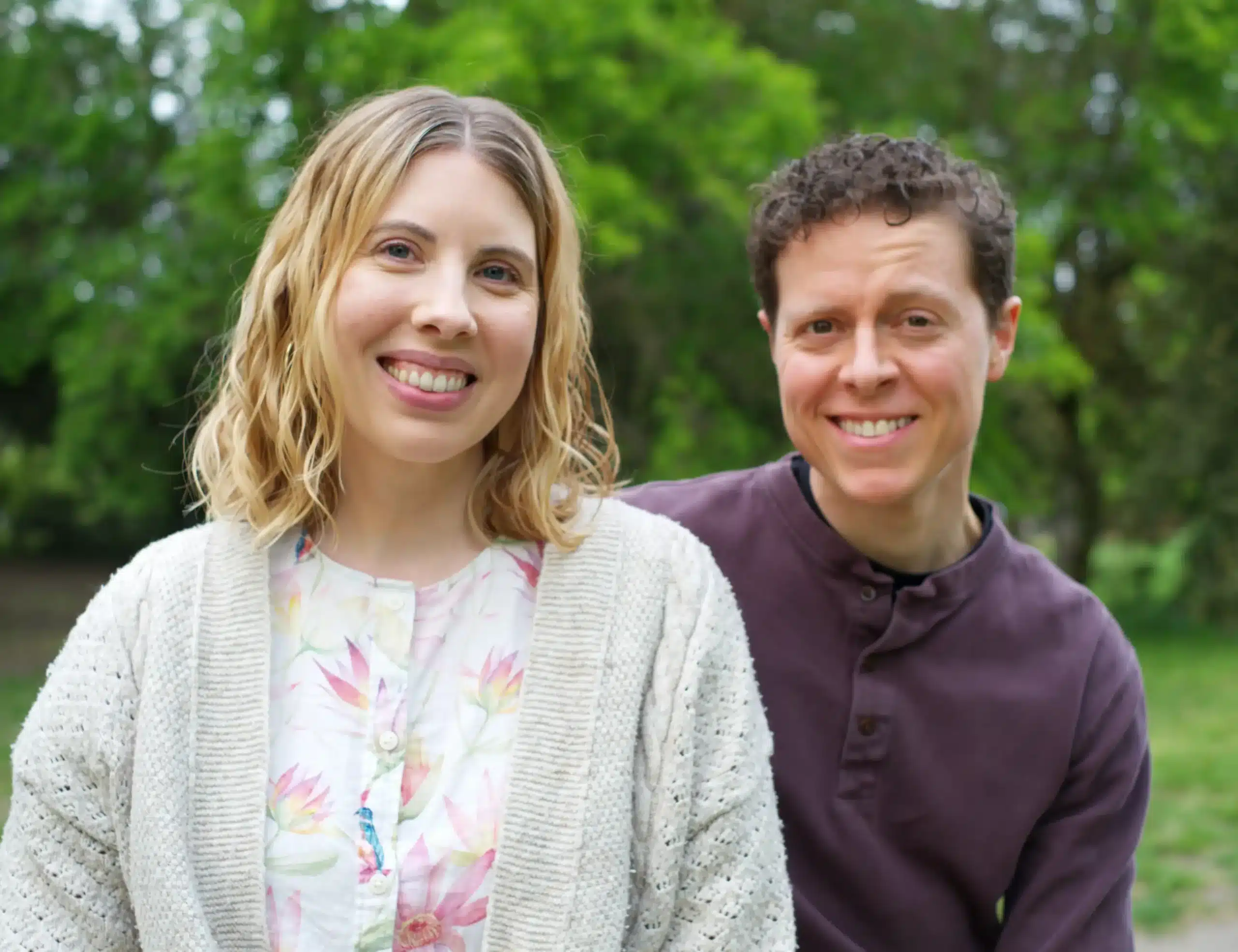 Stevie and Kit, founders of the Kit & Leaf family interiors blog, smiling outdoors surrounded by greenery.